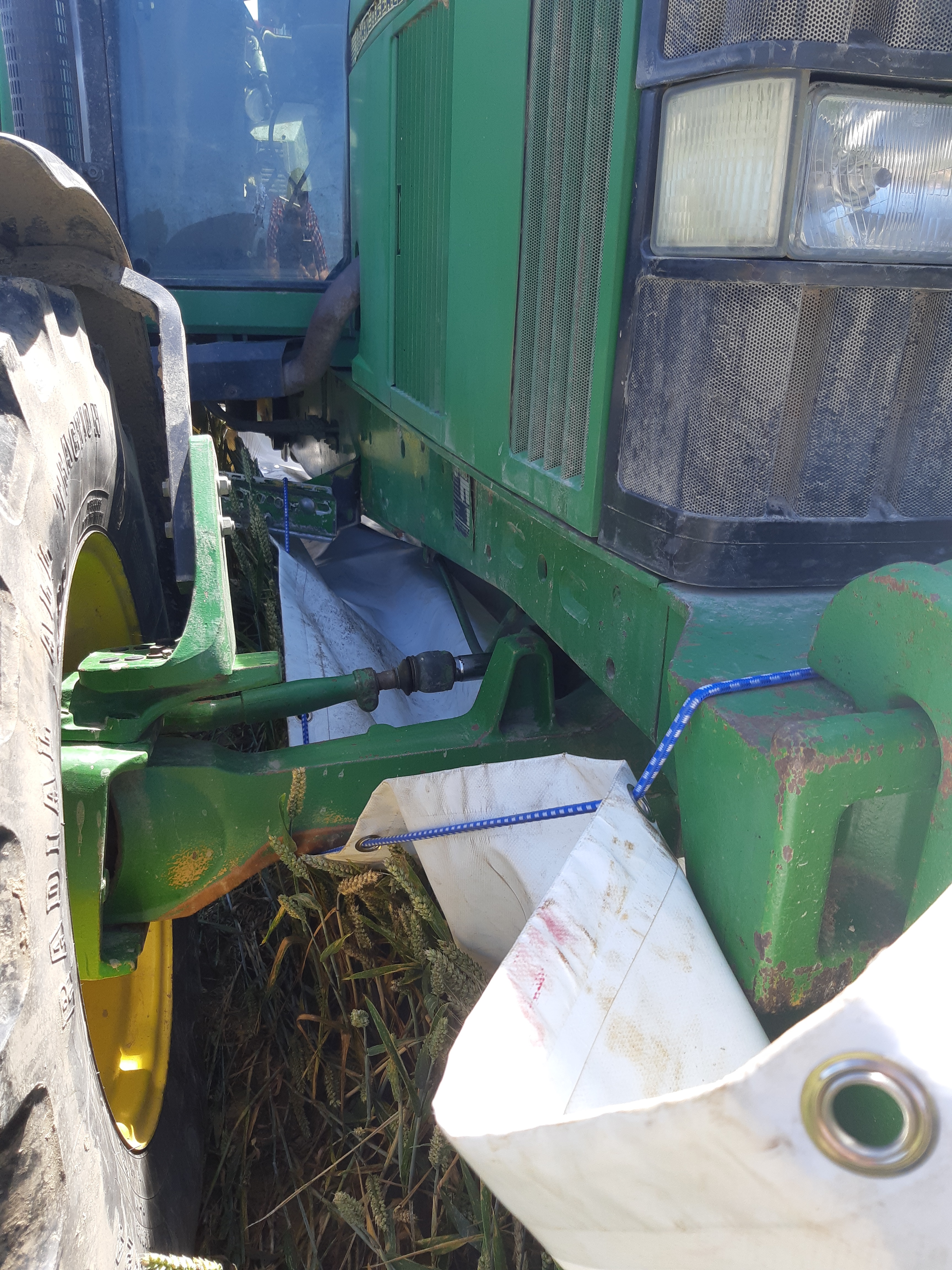 Une bâche qui rejoint l’avant (recouvre les masses ou le relevage avant) et l’arrière (bras de relevage) est fixée sous le tracteur afin d’éviter l’égrainage de l’orge au moment du semis.